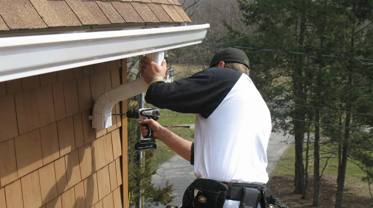 Professional contractor installing tan vinyl siding panels on a residential home exterior in Erie, PA
